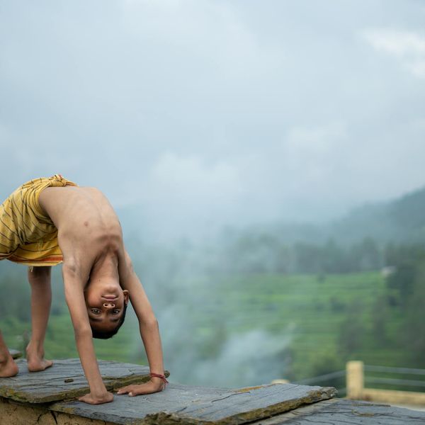 Person in an energetic yoga warrior pose against a dark background.